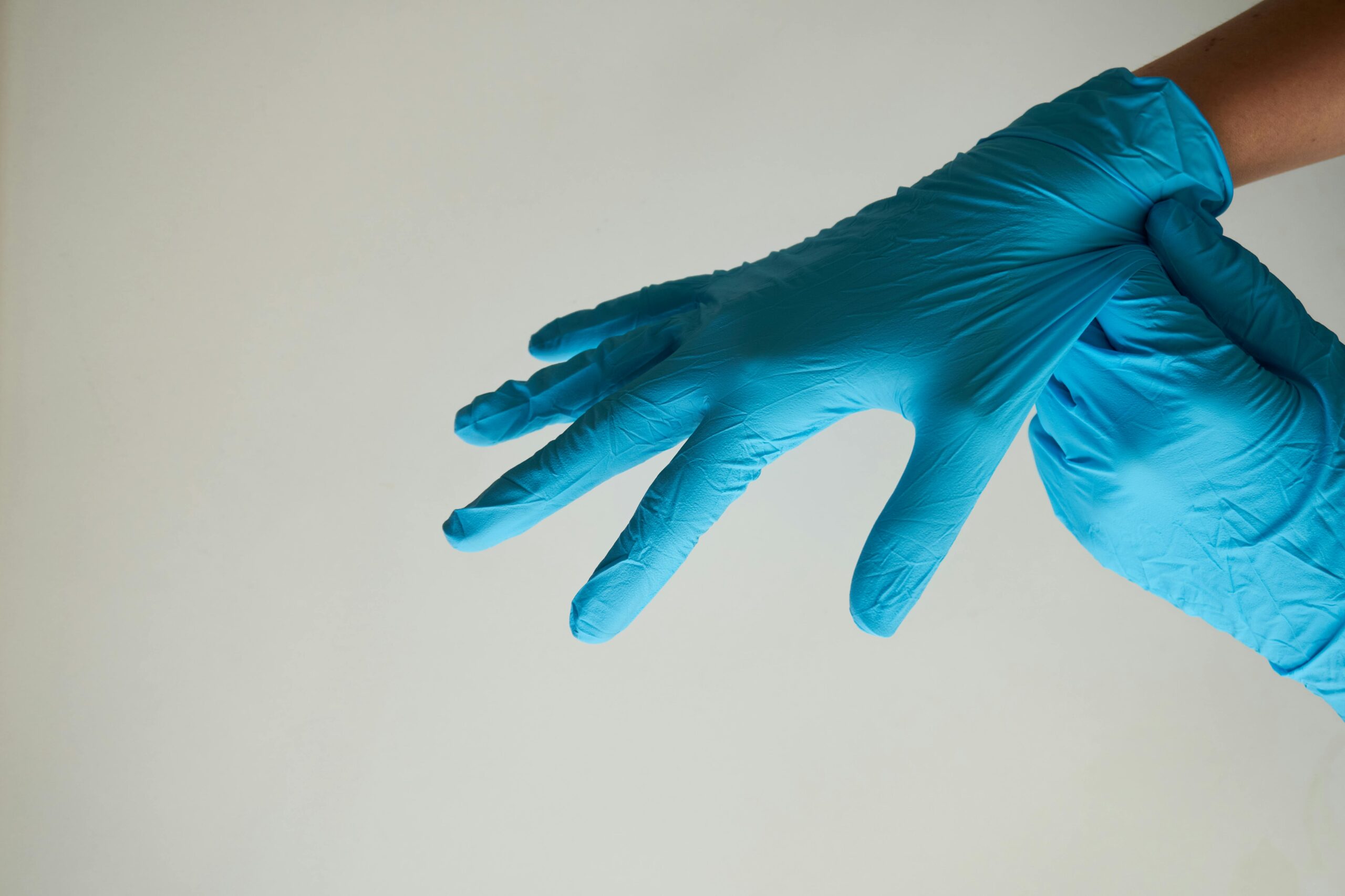 Hands wearing blue latex gloves, representing hygiene and safety.