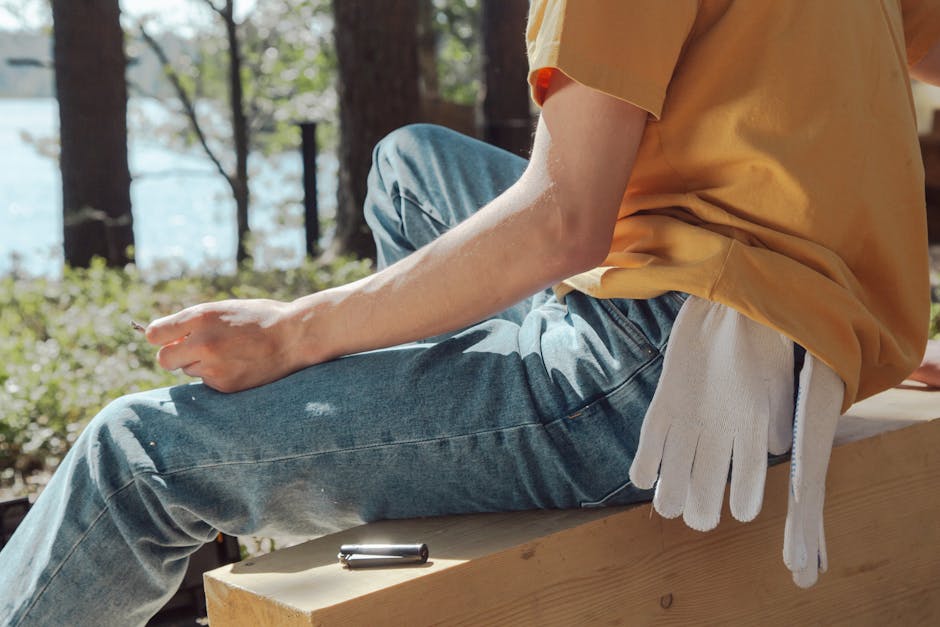 An unrecognizable person enjoys a break outdoors, holding a cigarette with gloves in pocket.